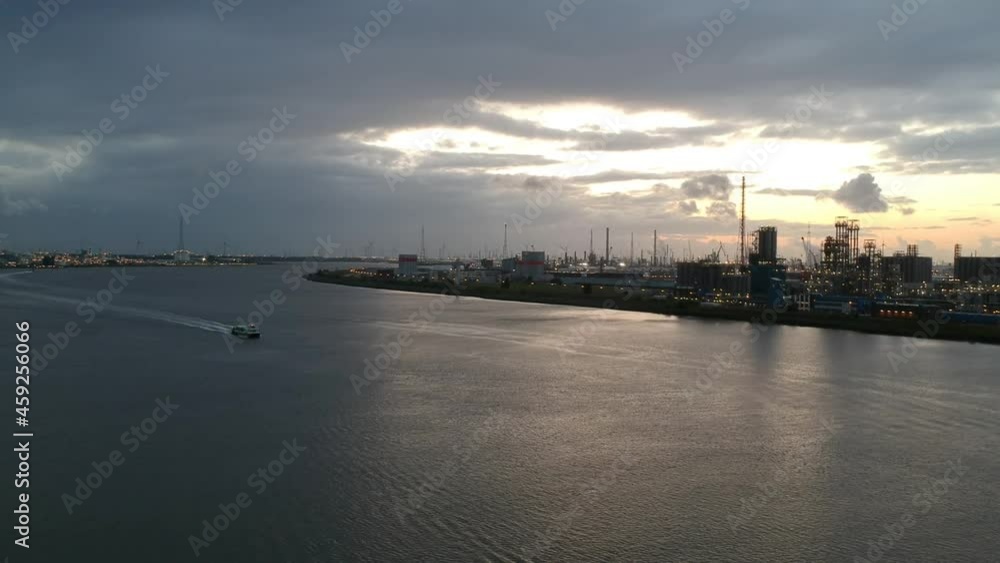 Industrial area of Antwerp harbor with single boat passing by, drone descend view Industrial area of Antwerp harbor with single boat passing by, drone descend view
