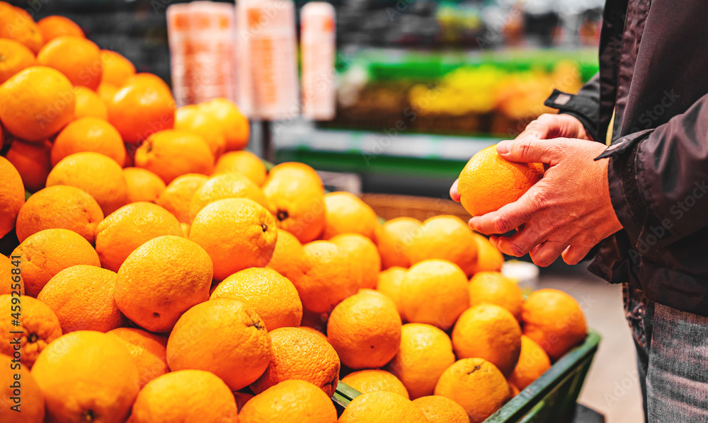 man hand holding orange in grocery store in supermarket