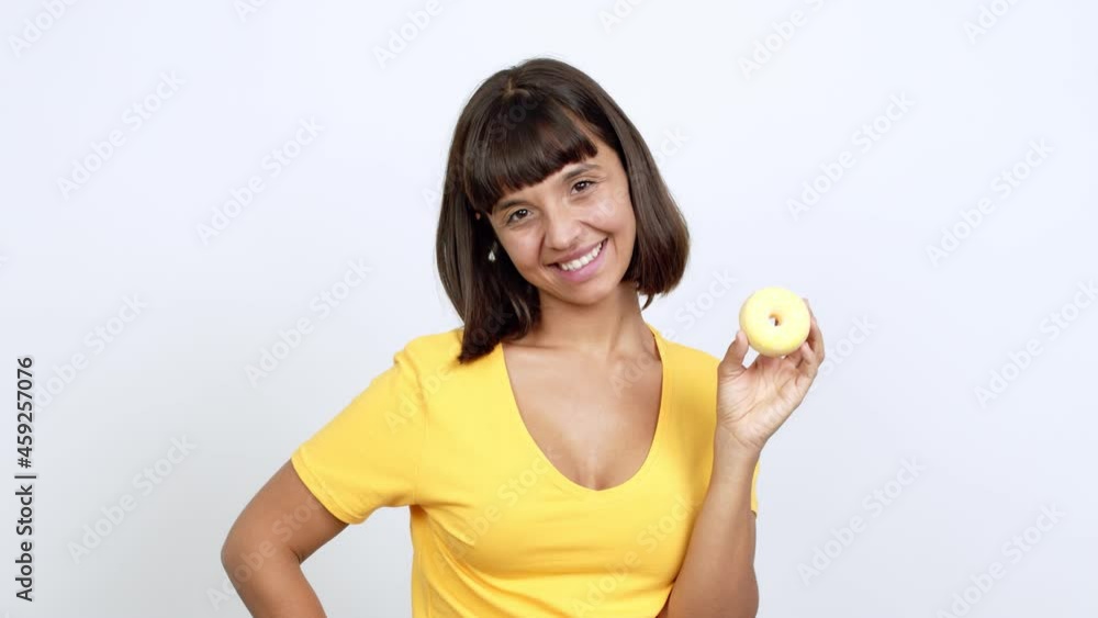 Young woman happy and holding a donut over isolated background Young woman happy and holding a donut over isolated background