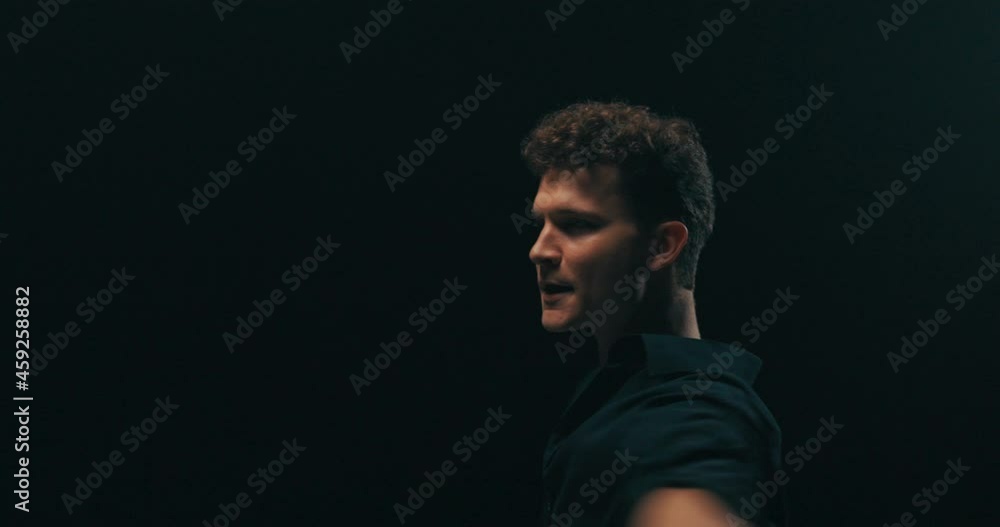 A professional experienced men is dancing on a dark stage lit by a lamp, practicing new moves, poses, the man has black shirt unbuttoned, he is a choreographer, showing steps to beginner dancers A professional experienced men is dancing on a dark stage lit by a lamp, practicing new moves, poses, the man has black shirt unbuttoned, he is a choreographer, showing steps to beginner dancers