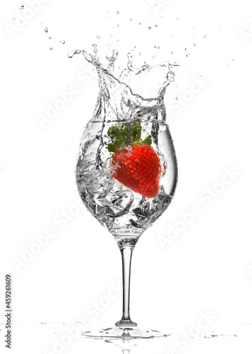 Strawberry splashing into an ice-cold cocktail glass isolated on white background