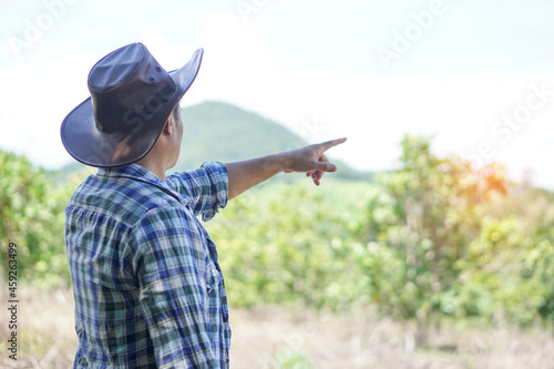 Asian male landowner point to show his boundary  in forest and mountain. Concept : Estate ,Land trading business. Plan project to do something. Adventure in forest. Travel, explore outdoor nature.  photo