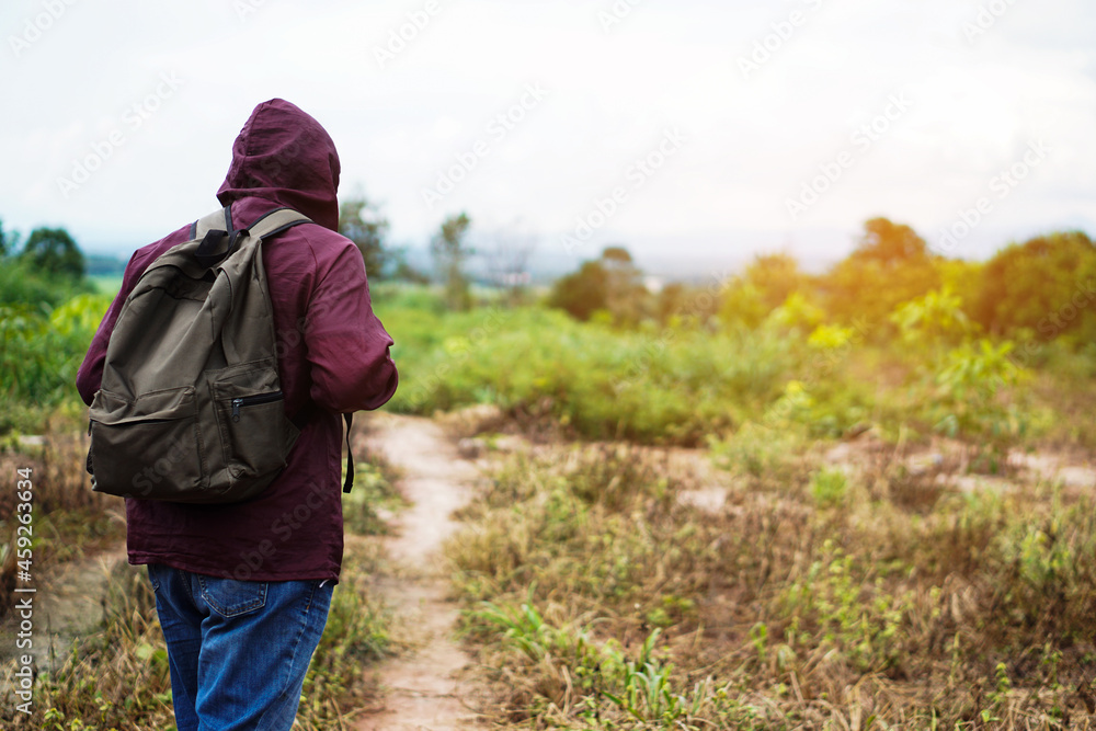 Back view of male traveler walking to forest. Concept : Eco traveling. Recreation on holiday. Trekking in the forest alone. Survival in forest. Copy space Back view of male traveler walking to forest. Concept : Eco traveling. Recreation on holiday. Trekking in the forest alone. Survival in forest. Copy space