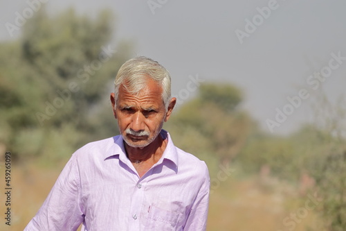 Photograph of an Indian resident senior man or self-sufficient aged farmer with defocused background of nature or forest