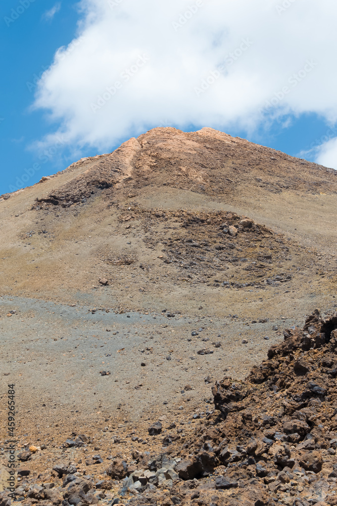 Close-up view of Teide volcano with a blue sky and a white cloud just over the top. 