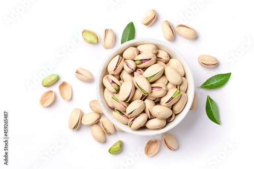 Flat lay of pistachio nuts in white bowl isolated on a white background.
