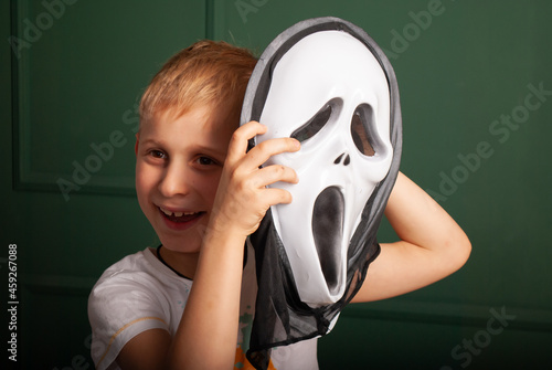 Konstfotografi a little boy with a theatrical mask in his hands on Halloween depicts laughter m