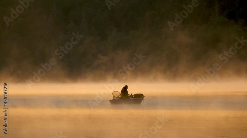 Morning fog on the lake at sunrise, man fishing from a boat, (Edersee, Germany)