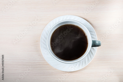 A white ceramic cup with black coffee with smoke