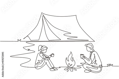 Single continuous line drawing camping or hiking couple around campfire tents. Man woman sitting on ground and drinking hot tea getting warm near bonfire. One line draw design vector illustration