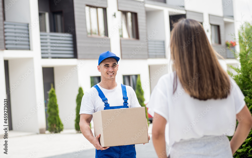 Young courier delivering goods to a young woman at home Young courier delivering goods to a young woman at home