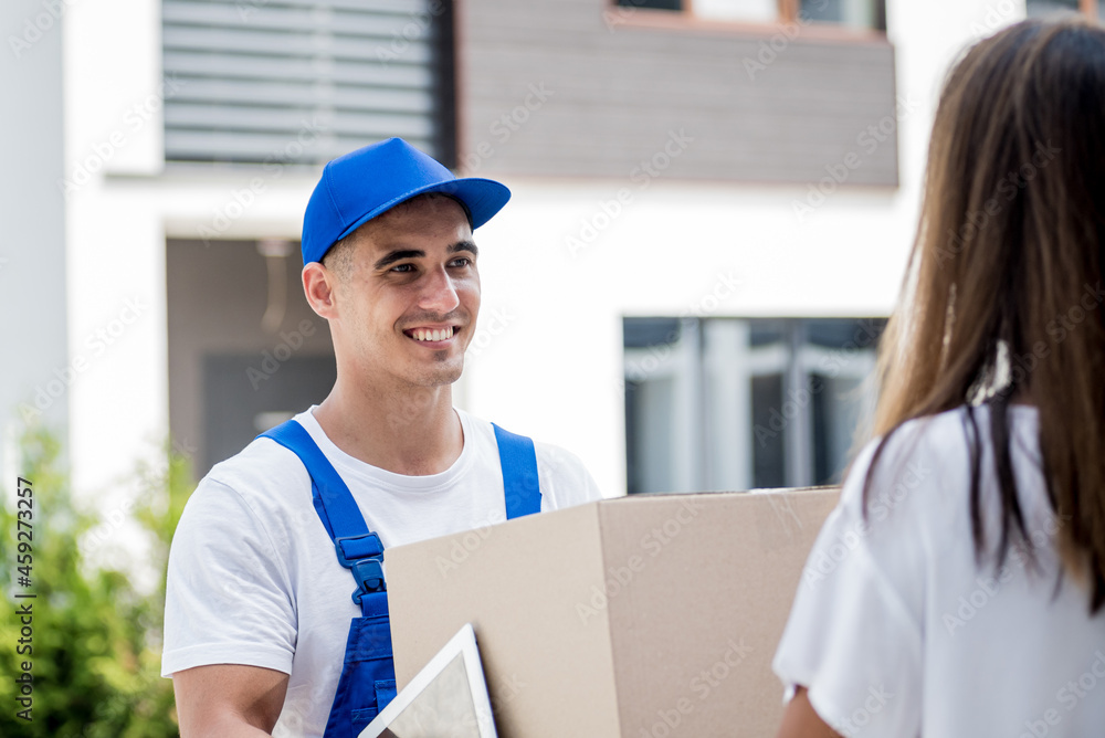 Young courier delivering goods to a young woman at home Young courier delivering goods to a young woman at home