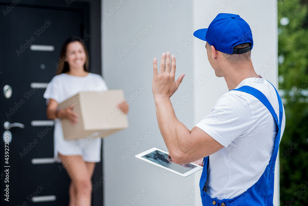 Young courier delivering goods to a young woman at home Young courier delivering goods to a young woman at home