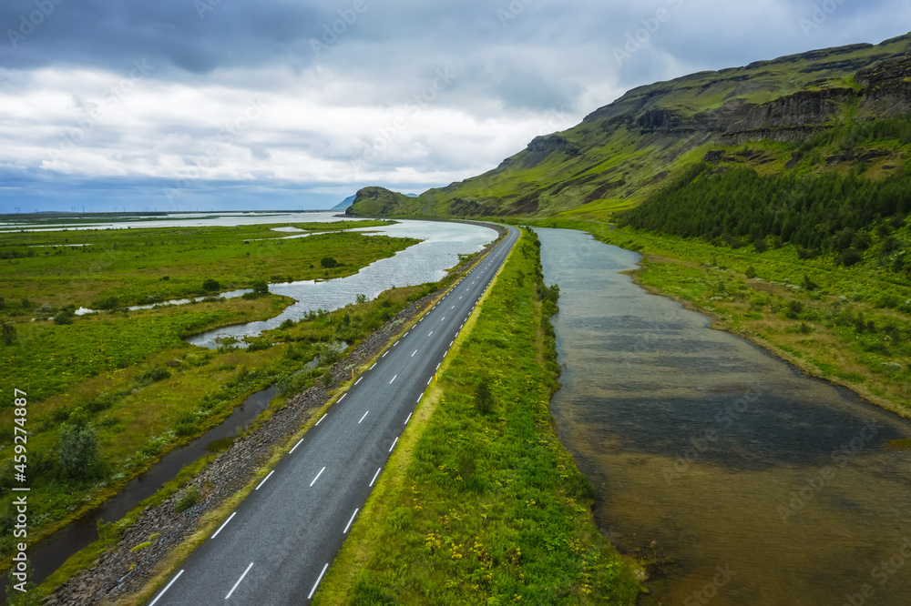 Obraz premium Iceland. Aerial view on mountain, field and river. Landscape in Iceland at the day time. View from drone. Summer. Cloudy weather. Fresh grass on field. Travel and vacation image