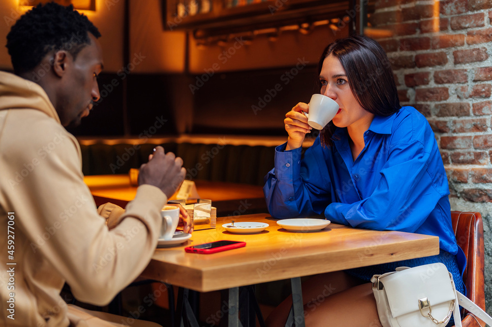 African American man drinking coffee in a coffee shop with a friend