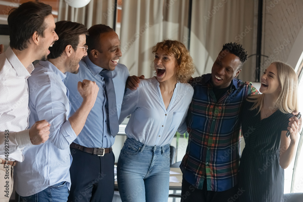 Group of happy excited diverse employees hugging, shouting for joy, celebrating teamwork success, win, good job result, achieve. Multiethnic business staff, united team of interns, workers portrait Group of happy excited diverse employees hugging, shouting for joy, celebrating teamwork success, win, good job result, achieve. Multiethnic business staff, united team of interns, workers portrait