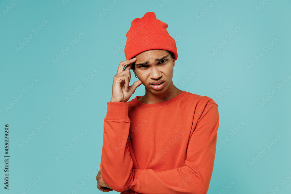 Young sad puzzled pensive thoughtful minded african american man 20s in orange shirt hat prop up forehead head isolated on plain pastel light blue background studio portrait. People lifestyle concept. Young sad puzzled pensive thoughtful minded african american man 20s in orange shirt hat prop up forehead head isolated on plain pastel light blue background studio portrait. People lifestyle concept.