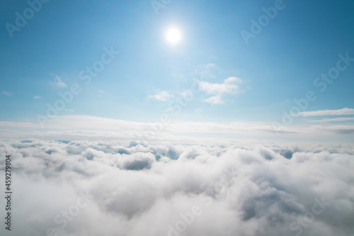 Aerial shot of white fluffy clouds and some blue sky in the distance while flying above the clouds. Aerial background. Beautiful cumulus clouds captured by a drone.