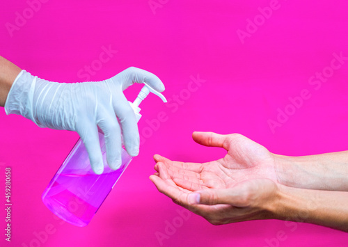 a gloved hand that sprays hand sanitizer on the other hand to protect it from bacteria and keep it hygenic.
