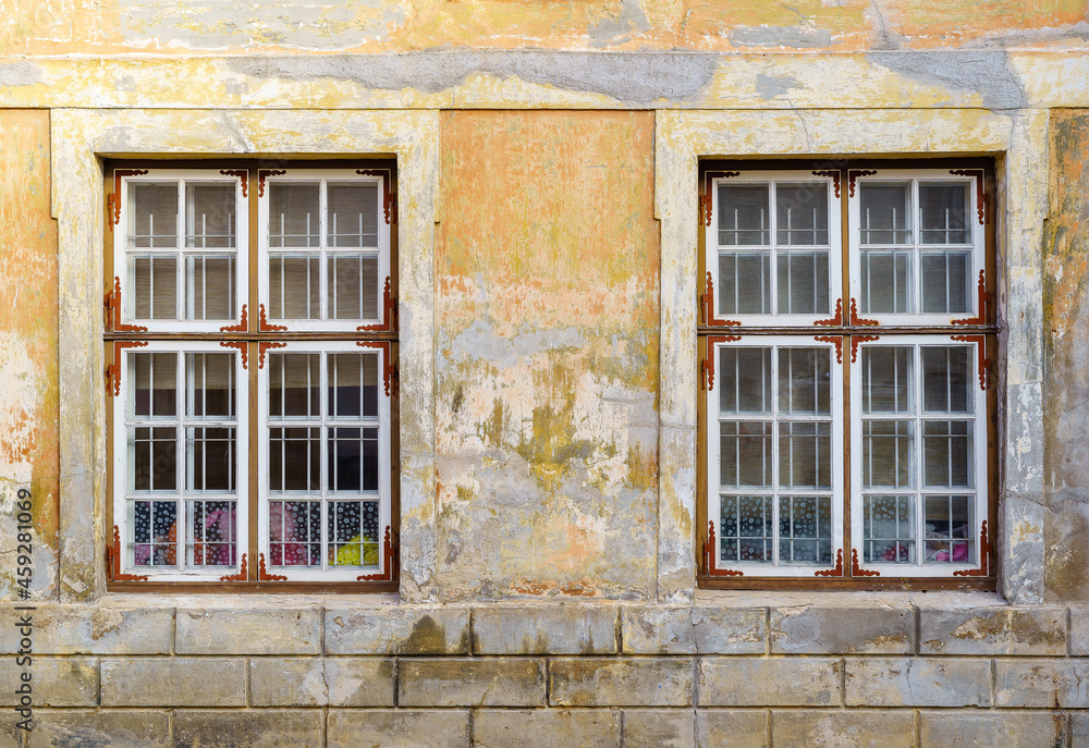 Old windows in stucco facade deteriorated by the passage of time.