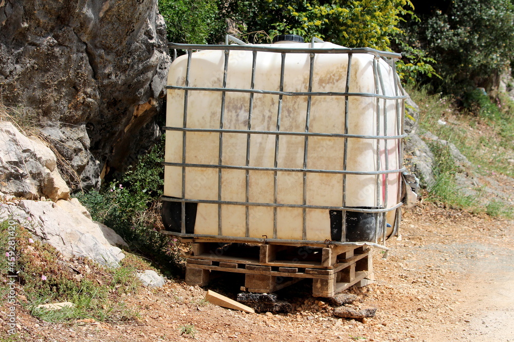 Beaten down old heavily used dirty white intermediate bulk container or ...