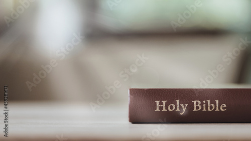 Holy Bible on wooden table against morning sunlight for prayer and bible study Christian devotion, copy space