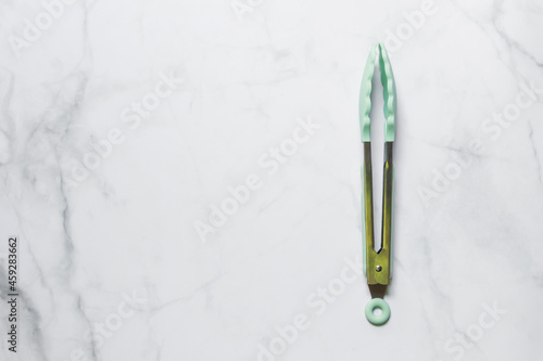 Silicone tongs isolated on white marble background; top view and copy space. photo