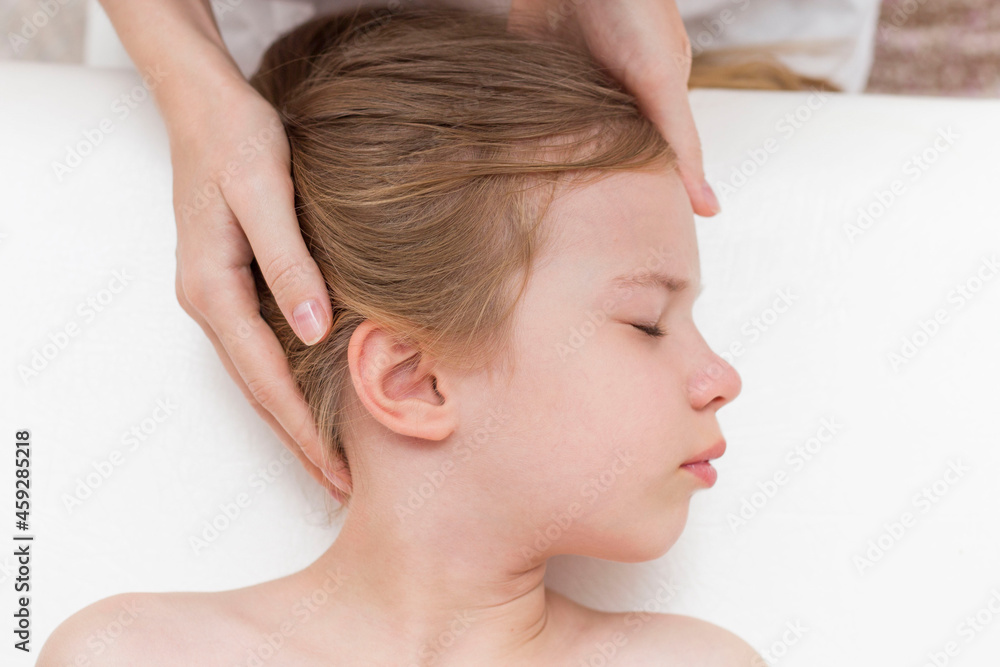 a seven-year-old girl at an appointment with an osteopath. Pediatric osteopathy. Headaches in school-age children. Correction of the skull, spine.