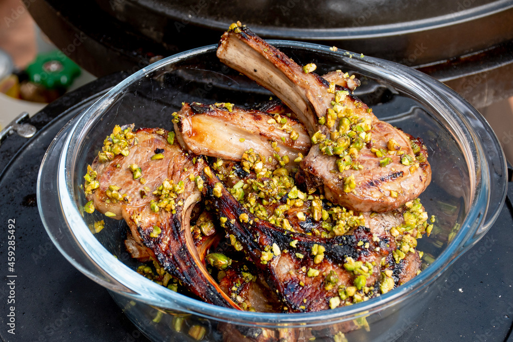 Lamb cutlets chops grilled on barbecue plate with pistachio nut . Backyard BBQ grill cooking. Australia Day celebration