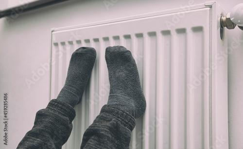 Boy warms legs near the radiator