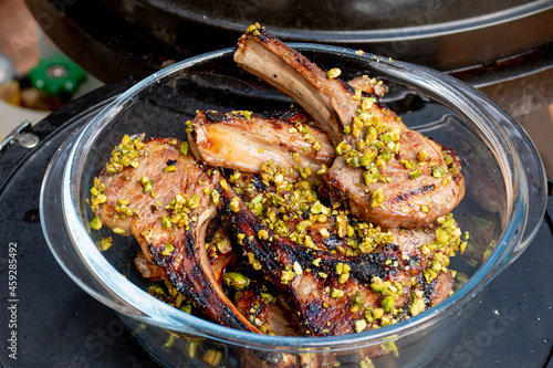 Lamb cutlets chops grilled on barbecue plate with pistachio nut . Backyard BBQ grill cooking. Australia Day celebration