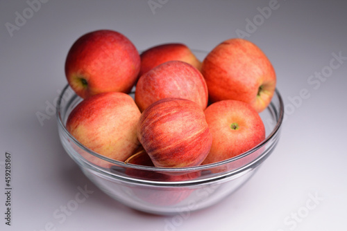 Glass bowl filled with red apples, isolated on grey background. Apples in bowl. Fresh ripe apples in bowl, selective focus.