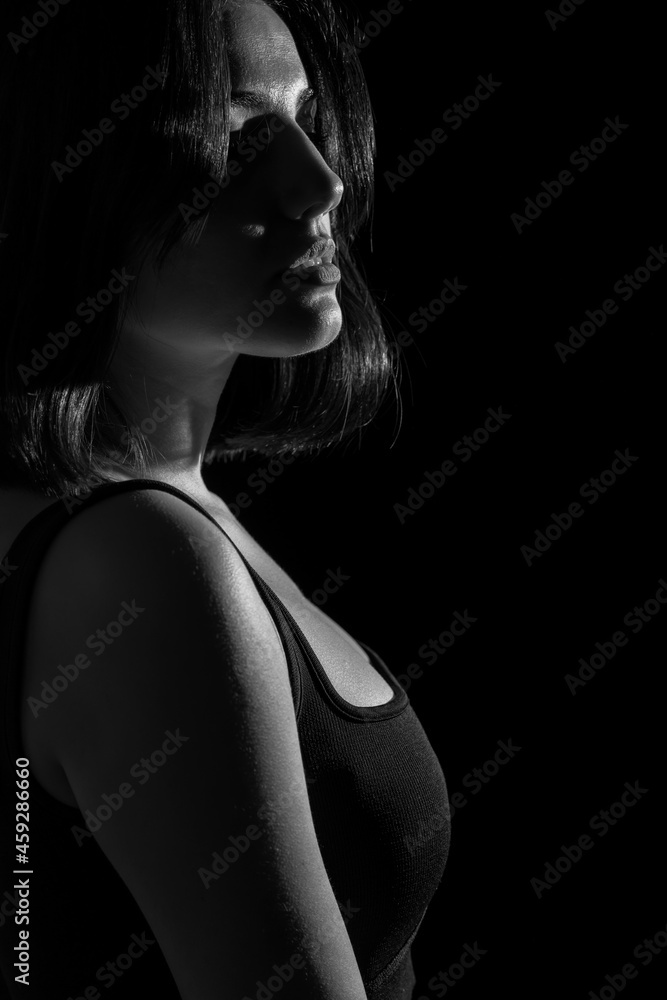 Naklejka premium Portrait of attractive a young woman with cinematic lighting. Woman wearing a suspender bodysuit. Half naked sexy woman. Vertical shot. Dramatic monochrome, black and white photo.