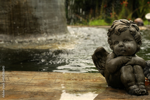 Angel kid statue on the park - green grass field