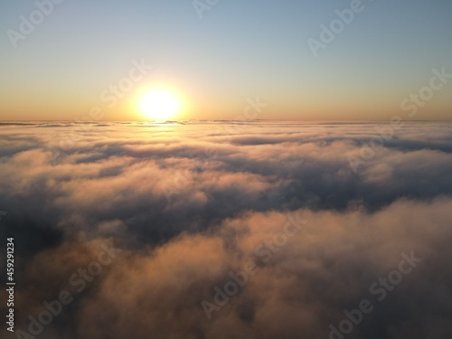 Dense fog clouds with the morning sunrise. Clouds formed over a lake approximately 100 feet below the clouds. Image could be drone an airplane window or drone.