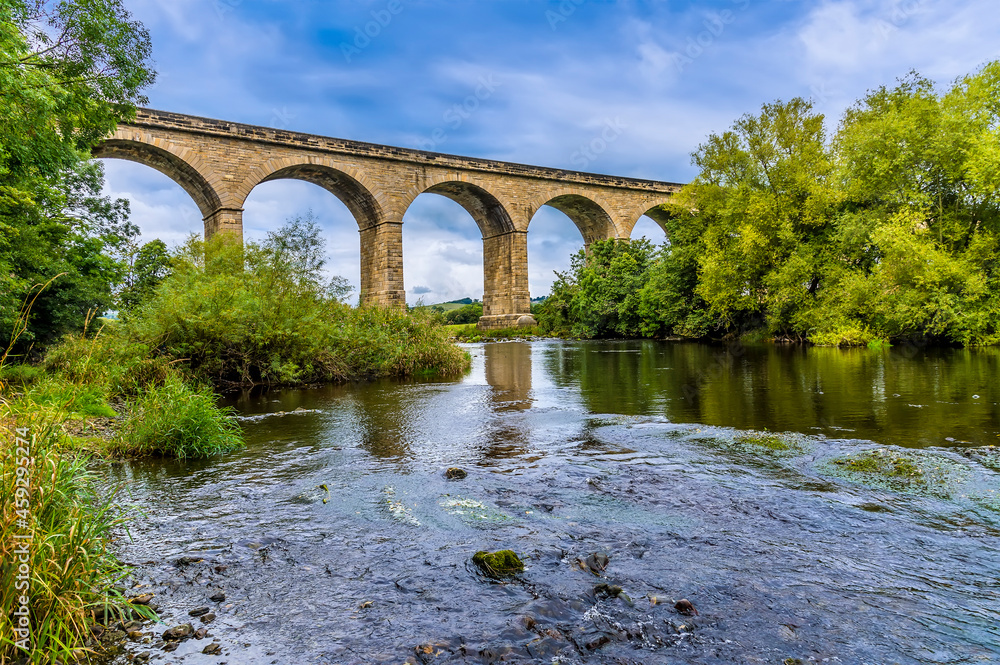 A view along the River Wharfe towards the Arthington Viaduct in Yorkshire, UK in summertime