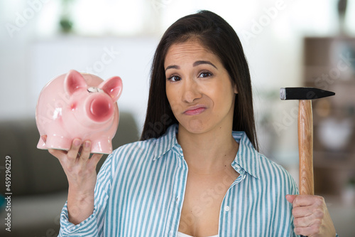 serious man breaking piggy bank with hammer photo