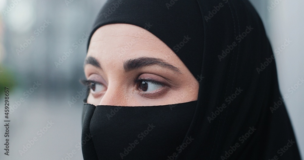 Cropped portrait view of the serious businesswoman wearing head scarf and protective mask standing at the street at the break and looking at the camera. Coronavirus pandemic concept Cropped portrait view of the serious businesswoman wearing head scarf and protective mask standing at the street at the break and looking at the camera. Coronavirus pandemic concept