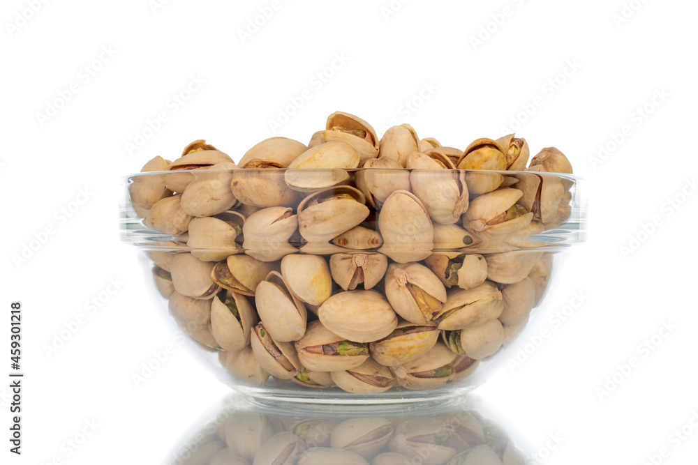 Lots of unpeeled pistachios in a glass dish, close-up, isolated on white. Lots of unpeeled pistachios in a glass dish, close-up, isolated on white.