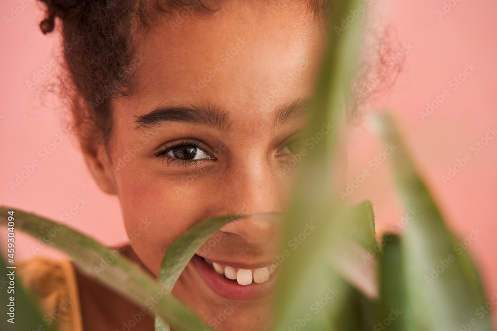 Little black girl behind leaves of green plant Little black girl behind leaves of green plant