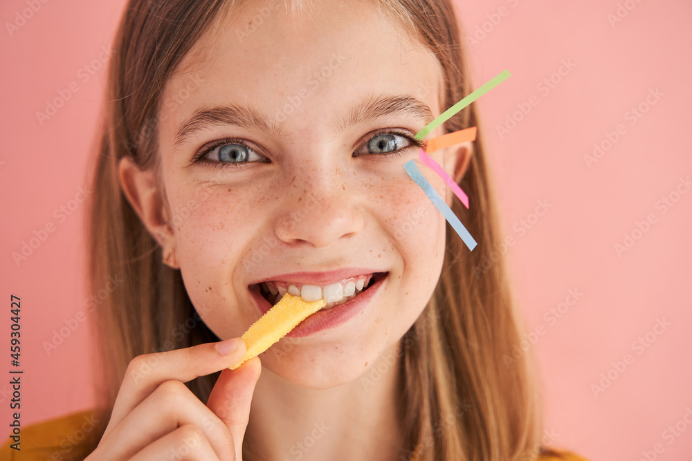 Little girl with stickers on her face eating candy Little girl with stickers on her face eating candy