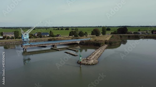 Blue old abandoned industrial crane at river Hollandse IJssel in the Netherlands, aerial flying towards the crane photo