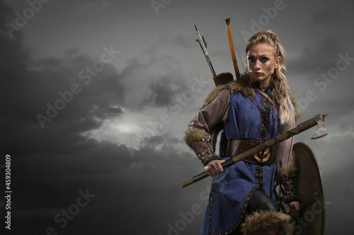 Beautiful female viking woman warrior in battle with ax and bow with arrows. Amazon fantasy blonde hair sexy girl