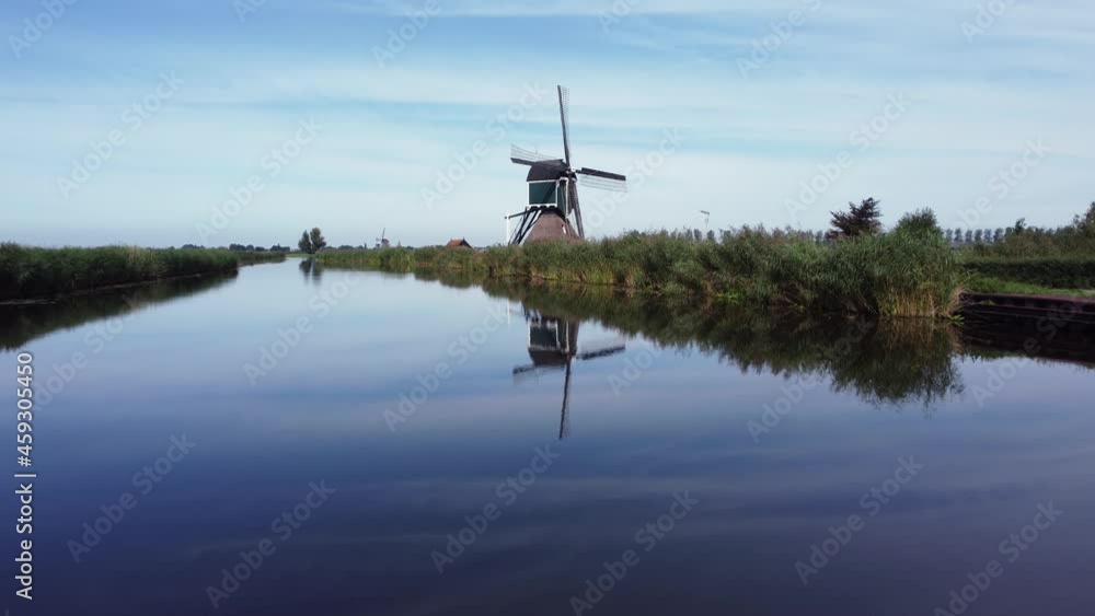 Old historic mill in Holland along riverside with reflection in water Old historic mill in Holland along riverside with reflection in water