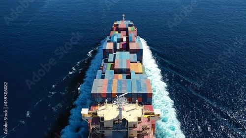 Aerial drone video above huge colourful container carrier vessel cruising deep blue open ocean sea photo