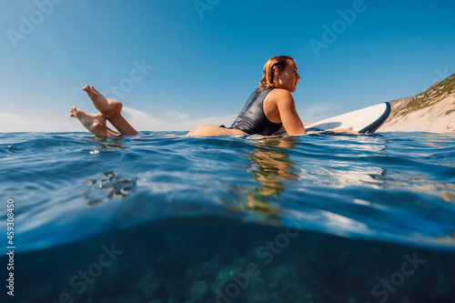 Surf girl floating on surfboard. Beautiful blonde woman during surfing. Surfer and ocean © artifirsov
