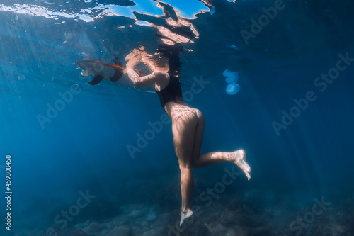 Surfer girl relaxing in sea. Underwater photo with woman and surfboard