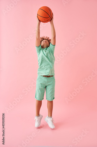 European little boy jumping with basketball ball