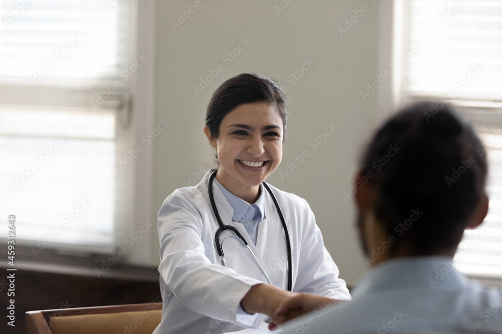 Happy successful young Indian doctor giving handshake to male patient in office, congratulating on recovery, good treatment result, smiling, finishing appointment with handshake, Healthcare concept Happy successful young Indian doctor giving handshake to male patient in office, congratulating on recovery, good treatment result, smiling, finishing appointment with handshake, Healthcare concept
