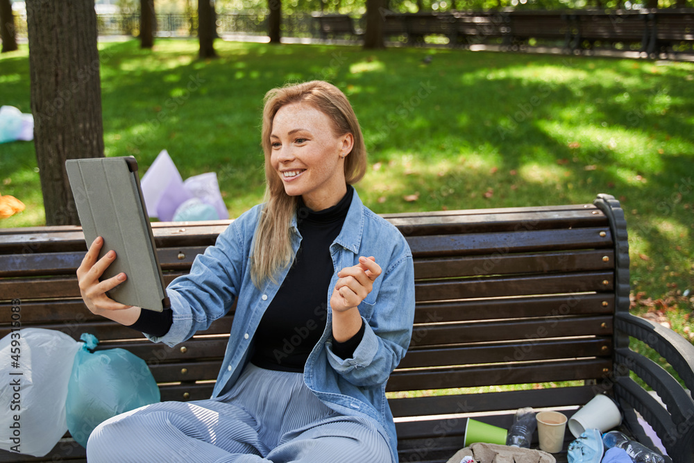 Woman video chatting at the tablet while sitting around the rubbish Woman video chatting at the tablet while sitting around the rubbish